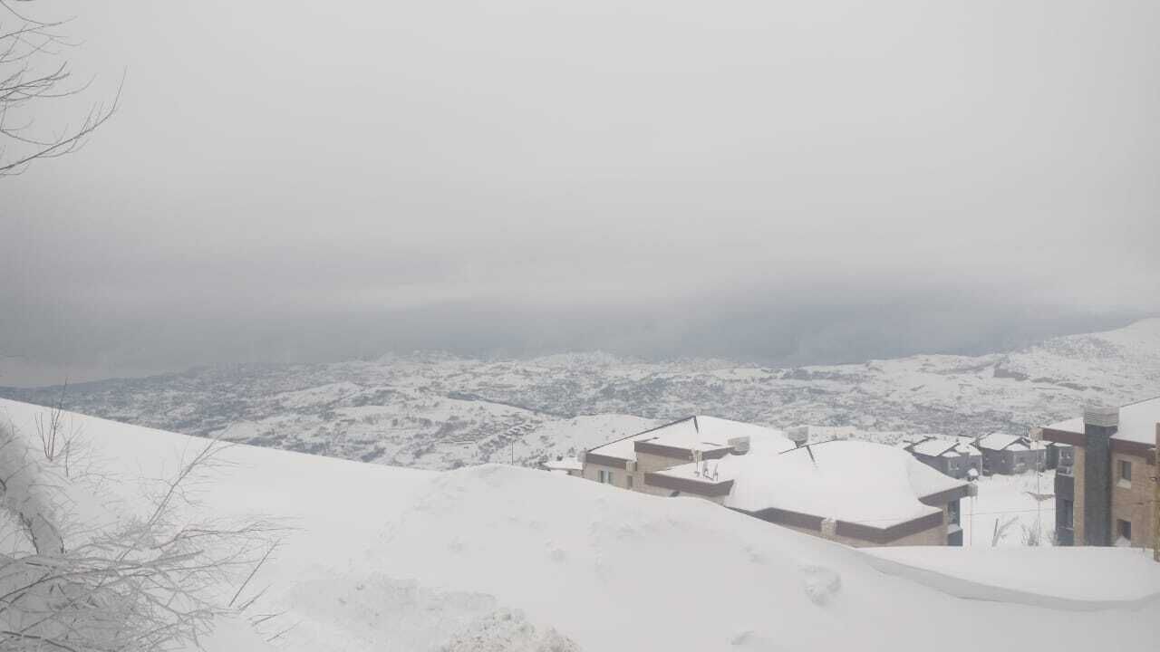 A snow-covered landscape with buildings in the foreground.