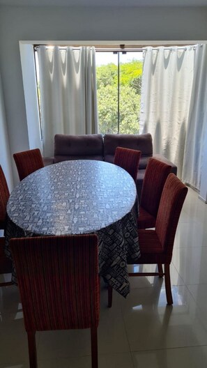 A dining area with a round table, red upholstered chairs, and a sofa. - Cobertura Vista Mar Jurerê Internacional (Florianópolis)