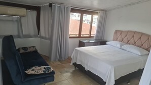 A hotel room with a bed, a chair, a desk, and a window with curtains. - Cobertura Vista Mar Jurerê Internacional (Florianópolis)