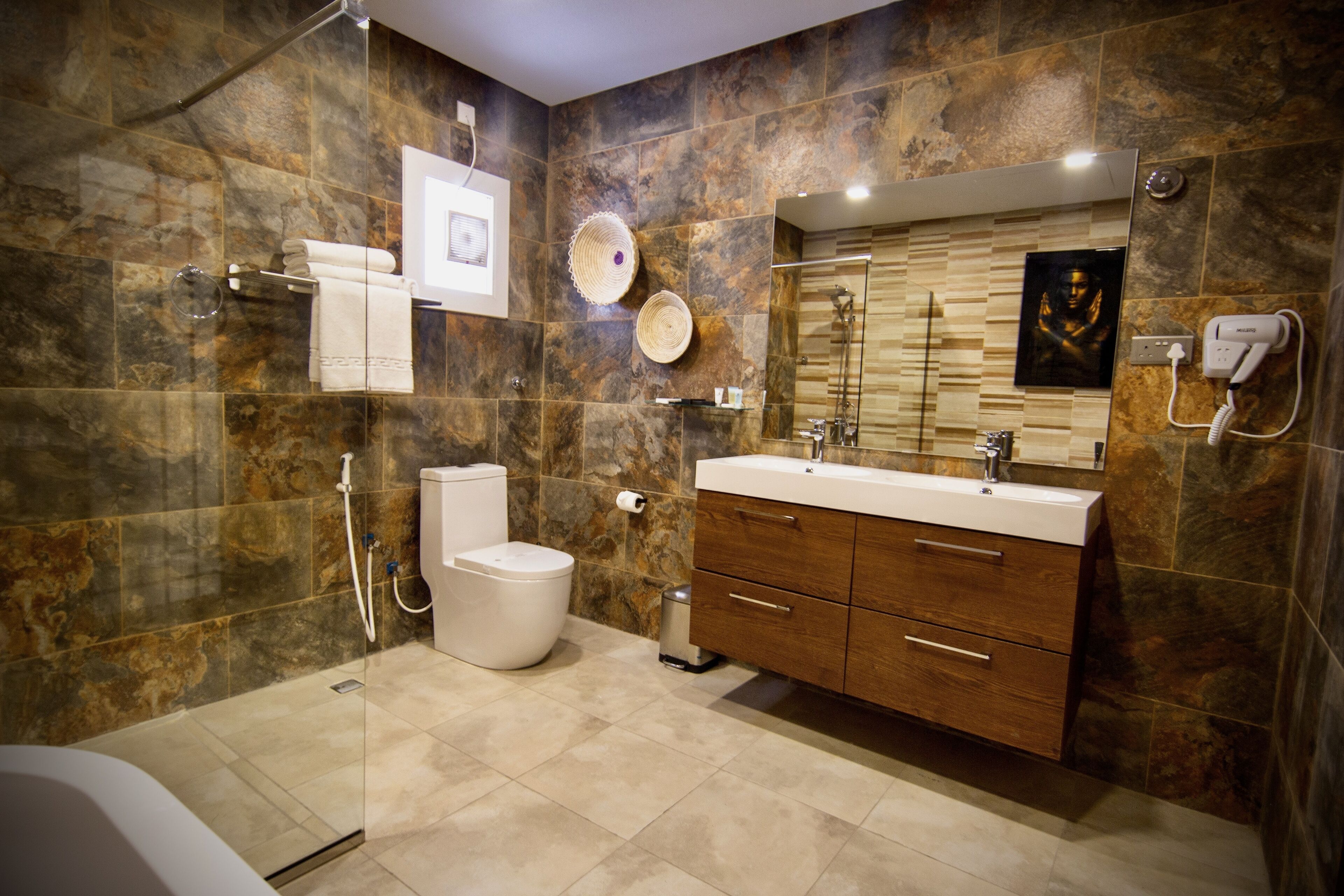 A modern bathroom with a shower, toilet, vanity, and a large mirror.