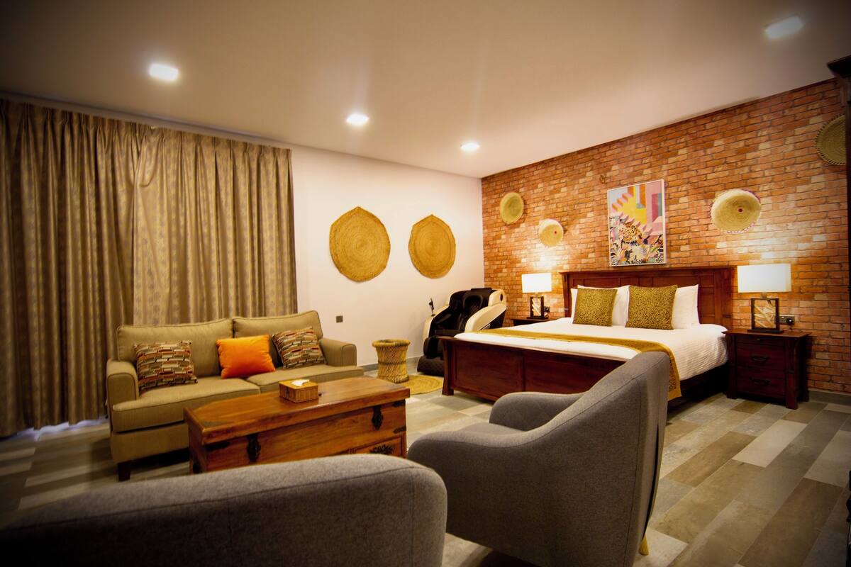 Quarto de hotel moderno com uma cama grande, um sofá, uma mesa de centro e uma área de estar.