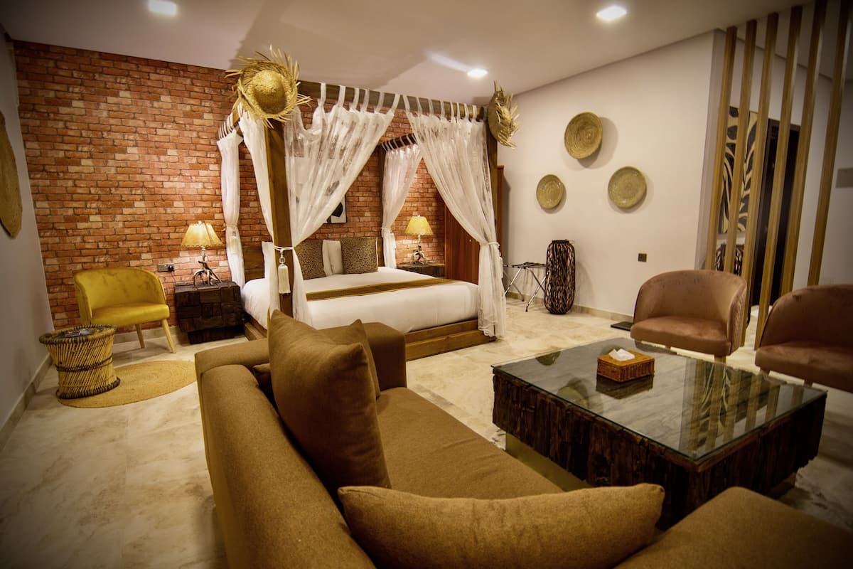 Um quarto com cama, sofá, mesa de centro, poltrona e luminária.