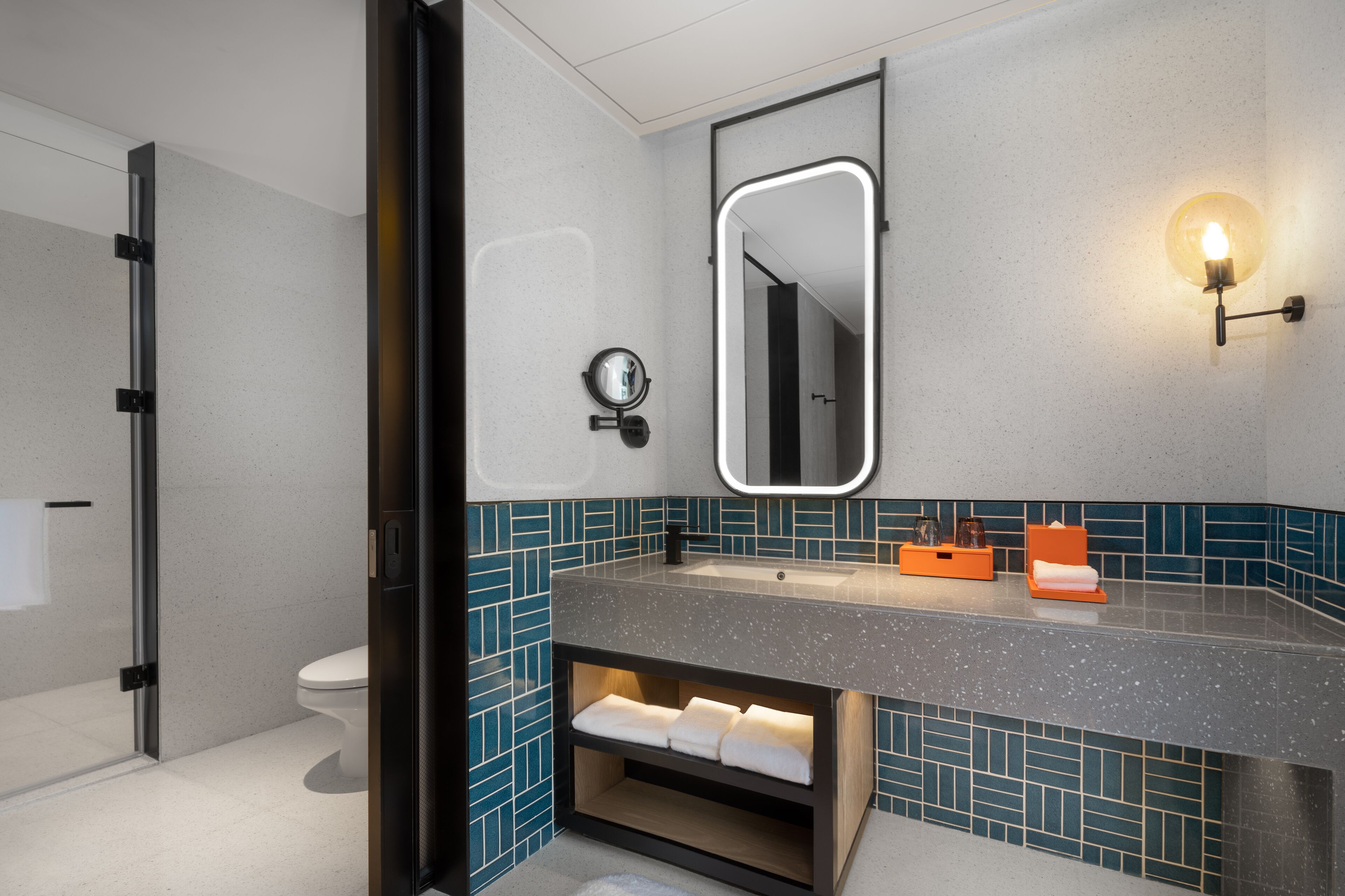 Un baño moderno con cabina de ducha de vidrio, un lavabo con espejo y un perchero para toallas.
