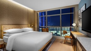 A modern hotel room with a large bed, a desk, and a view of a cityscape at night. - Four Points by Sheraton Chongqing, Yongchuan (Chongqing)