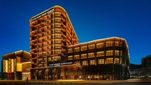 A modern hotel with a curved facade, multiple floors, and illuminated signage. - Four Points by Sheraton Chongqing, Yongchuan (Chongqing)