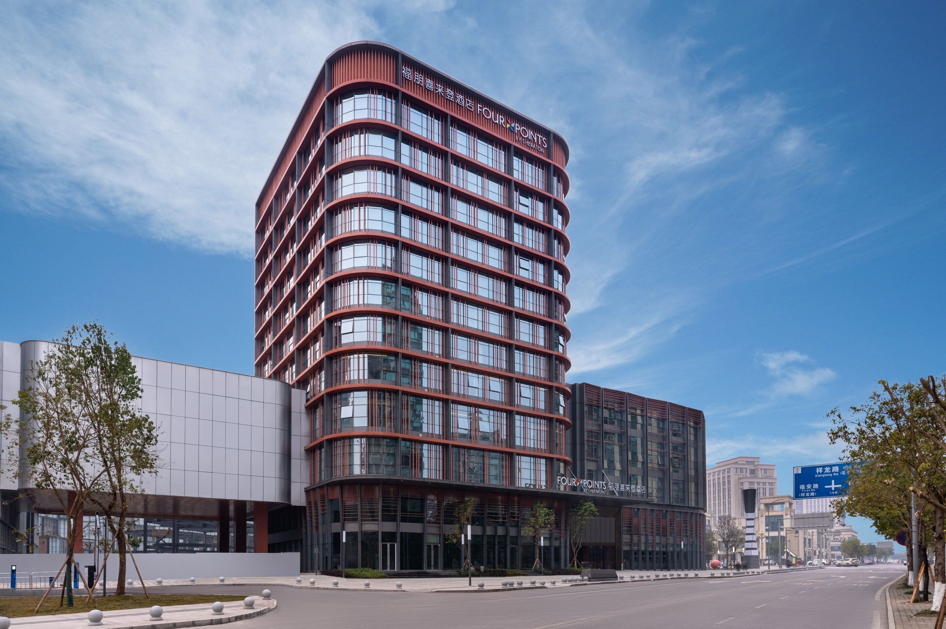 A modern hotel with a curved facade, multiple floors, and large windows.