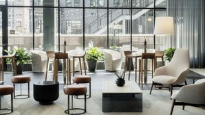 A modern lounge area with seating, tables, and potted plants.