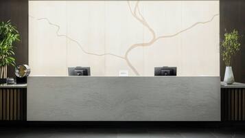 A reception desk with a minimalist design, two black speakers, and a wall with a tree-like pattern.