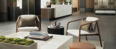 A modern lobby with seating areas, a reception desk, and decorative plants.