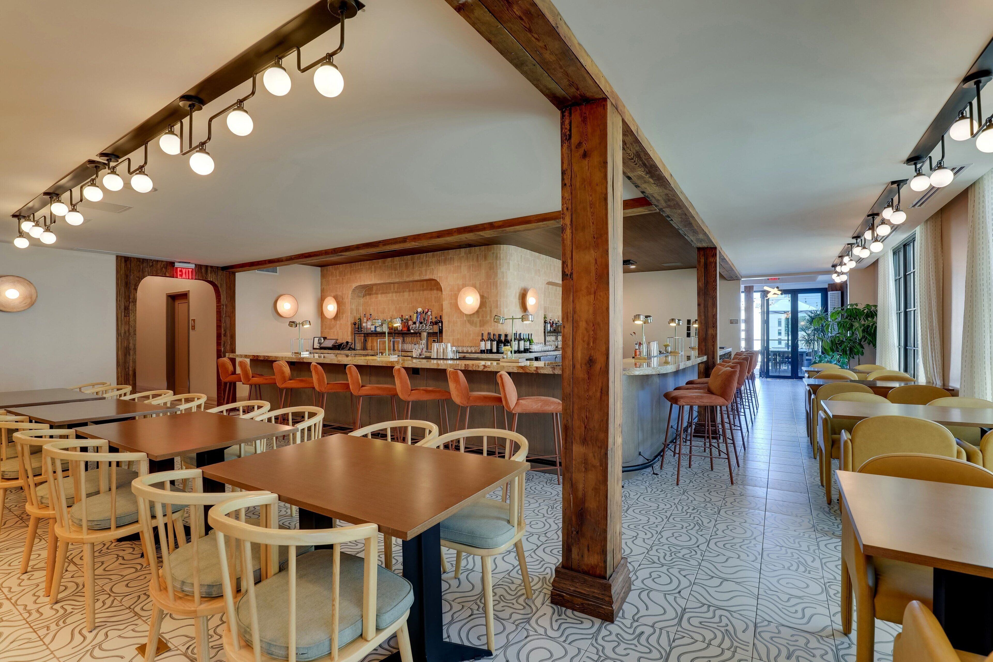 A restaurant with wooden tables and chairs, a bar area, and patterned flooring.