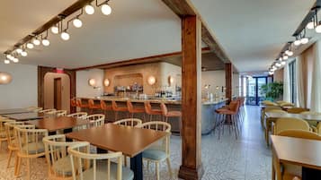 A restaurant with wooden tables and chairs, a bar area, and patterned flooring.