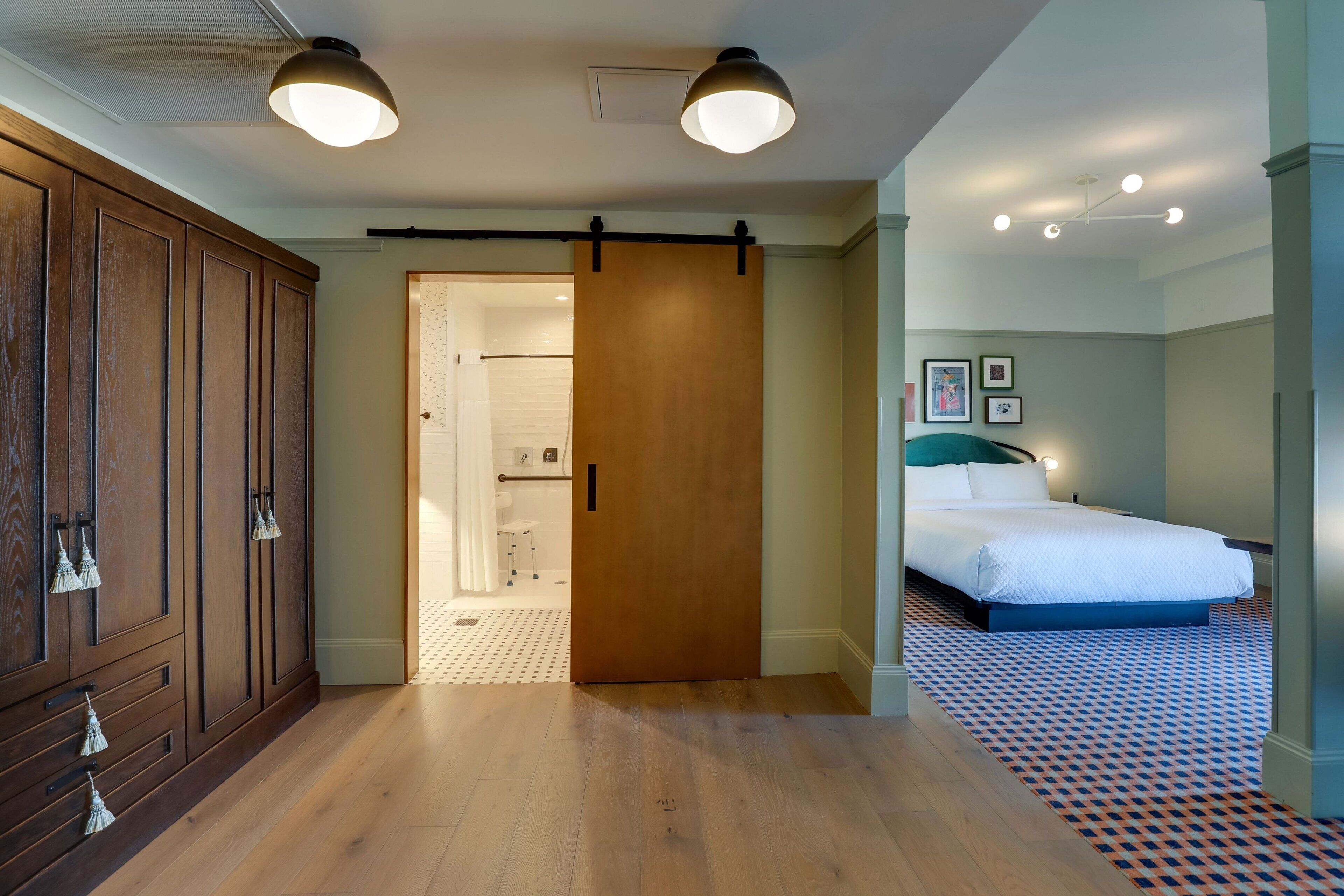 Una habitación de hotel con un armario de madera, una cama con cabecera azul y un suelo estampado.
