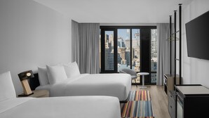 A hotel room with two beds, a desk, a chair, a TV, and a view of the cityscape. - Aloft by Marriott New York Chelsea (New York)