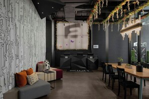 A modern hotel lobby with geometric patterned walls, a reception desk, seating area, and a view of the cityscape through large windows. - Aloft by Marriott New York Chelsea (New York)