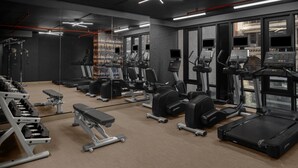A modern gym with treadmills, weight machines, and a mirrored wall. - Aloft by Marriott New York Chelsea (New York)