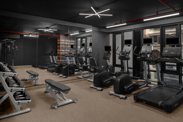 A modern gym with treadmills, weight machines, and a mirrored wall.