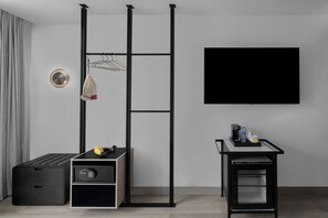 A modern room with a black storage unit, a wall-mounted TV, and a small table with a coffee maker.