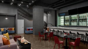 A modern lounge area with a staircase, seating arrangements, and a bar area. - Aloft by Marriott New York Chelsea (New York)