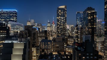 A cityscape at night with illuminated buildings and a prominent tower in the background.