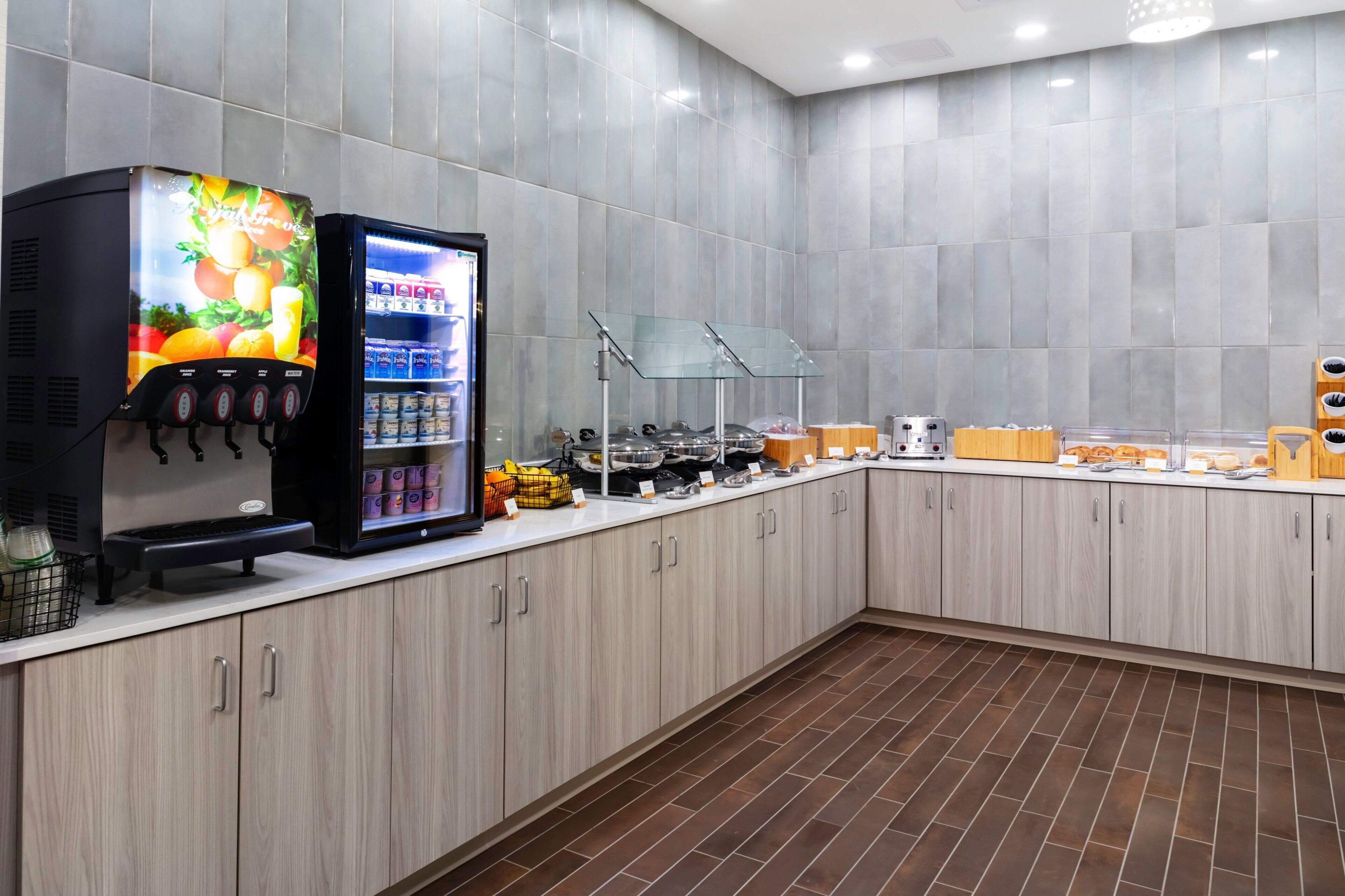 A modern kitchen with a coffee machine, a refrigerator, and a variety of food items on the counter.
