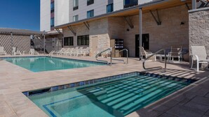 A pool area with two pools, lounge chairs, and a covered seating area. - TownePlace by Marriott Suites Buckeye Verrado (Buckeye)