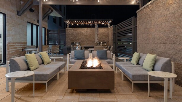 An outdoor seating area with a fire pit, cushioned sofas, and tables. - TownePlace by Marriott Suites Buckeye Verrado (Buckeye)