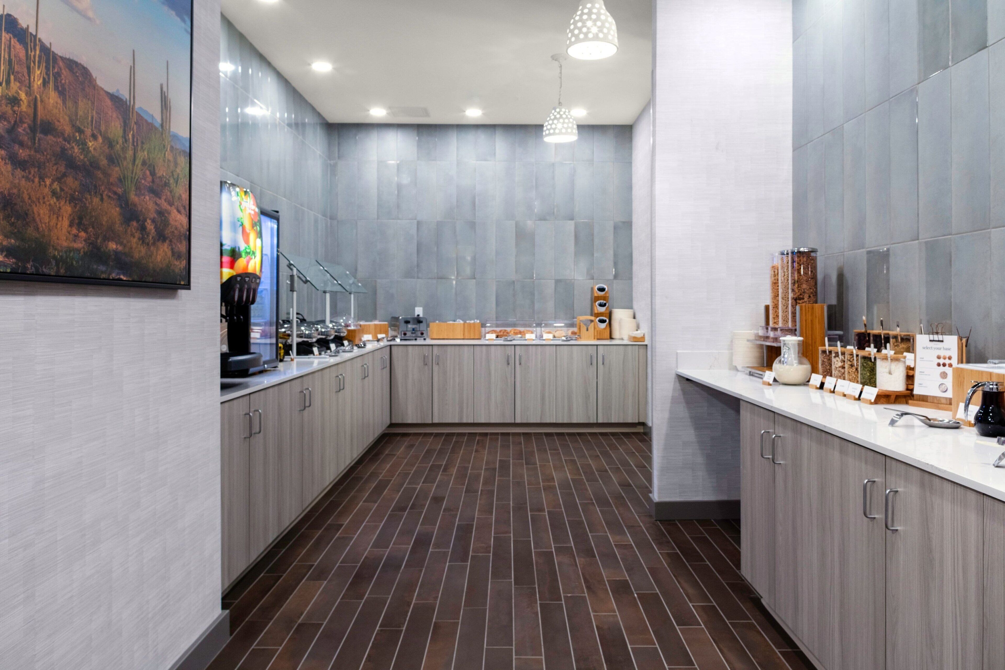 A modern kitchen with grey cabinets, a tiled floor, and a large painting on the wall.