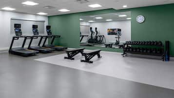 A gym with treadmills, elliptical machines, and weight benches.