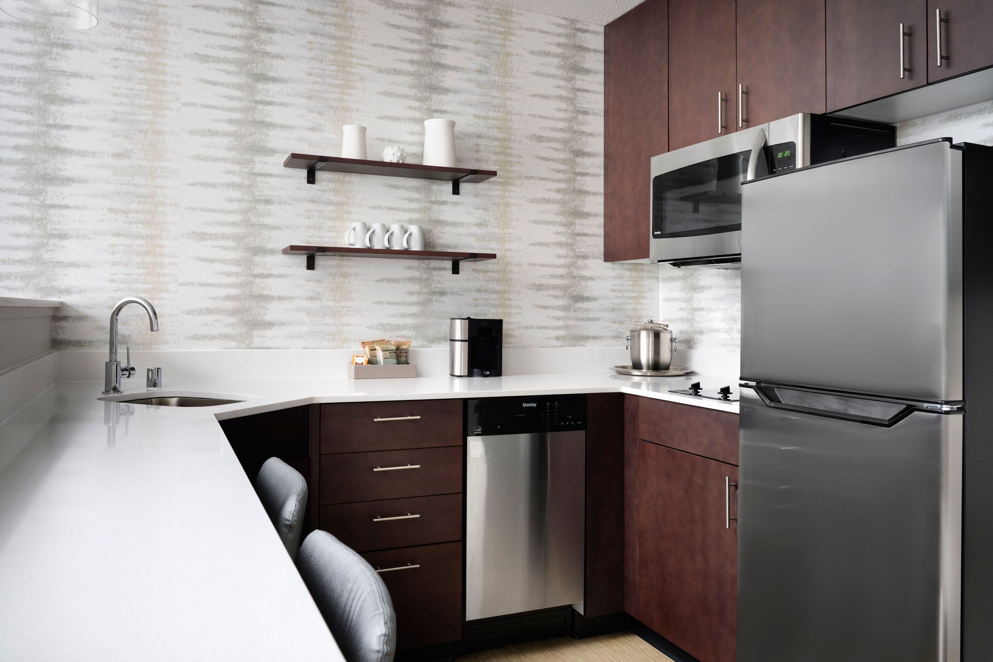 A modern kitchen with a dishwasher, stainless steel appliances, and wooden cabinets.