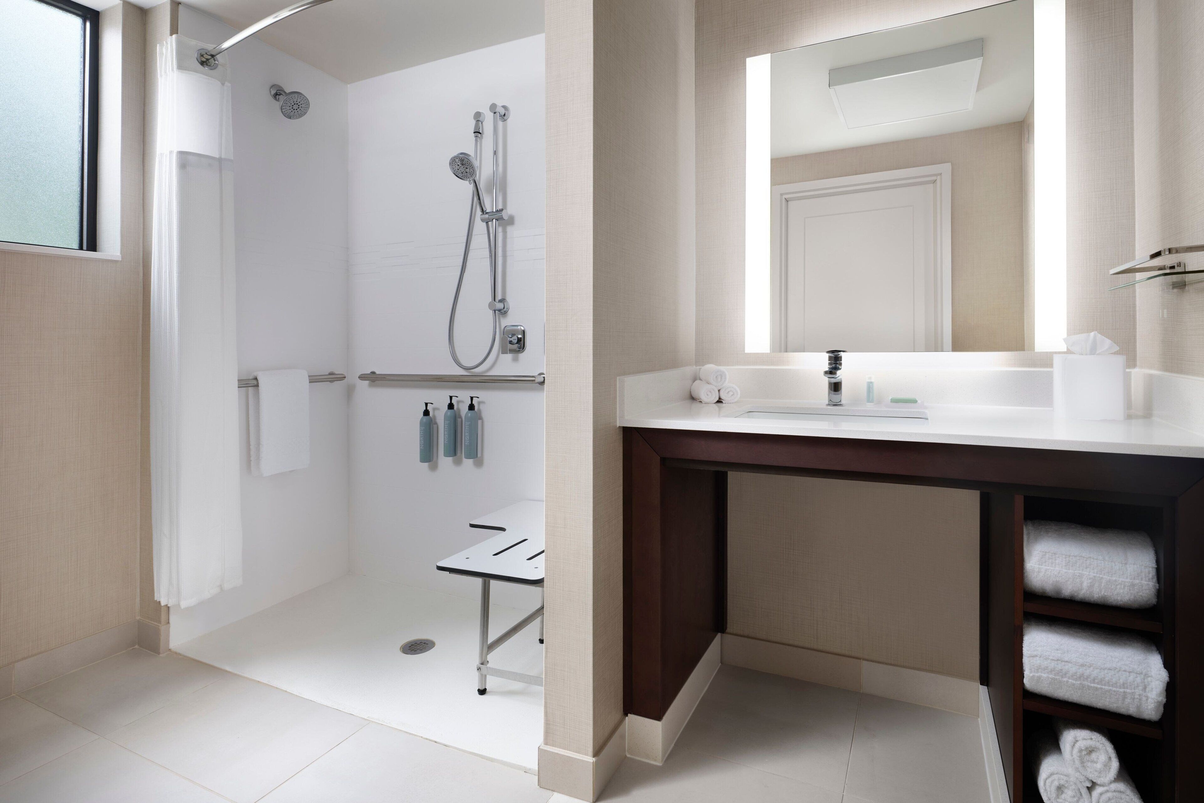 A modern bathroom with a shower, vanity, and a mirror.