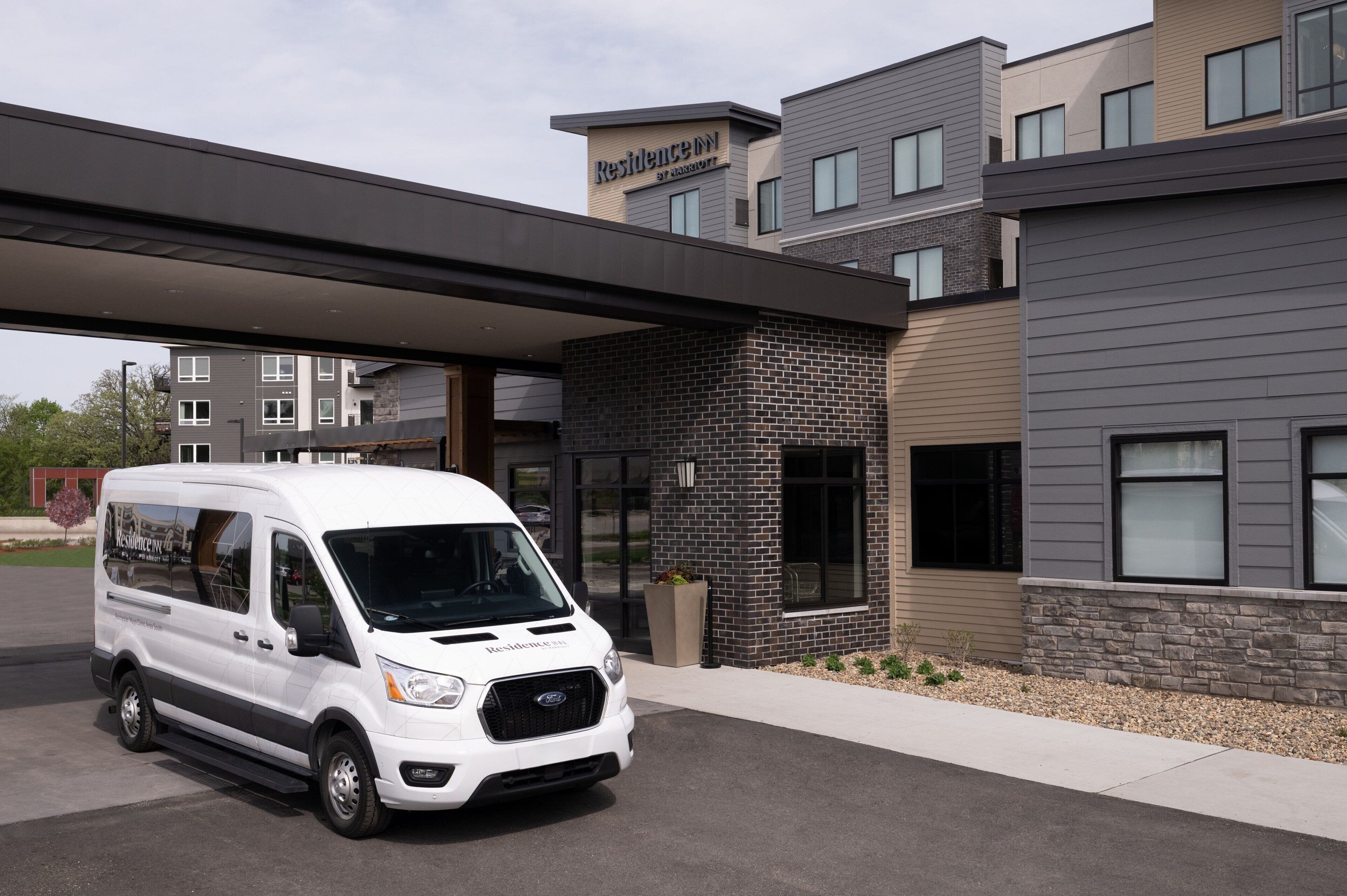 Un fourgon blanc est garé devant un bâtiment moderne sur lequel on peut lire l’inscription « Residence Inn ».