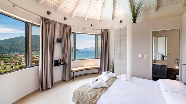 A hotel room with a large bed, a bench, a view of the sea, and a balcony. - Villa Maria 2 Drakatos (Lefkada)
