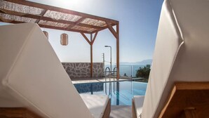 A poolside area with lounge chairs and a pergola, overlooking a pool and a scenic view. - Villa Petalouda Paleros (Aktio-Vonitsa)