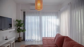 A modern living room with a sofa, a coffee table, a TV, and a potted plant. - Villa Petalouda Paleros (Aktio-Vonitsa)