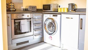A compact kitchen with a built-in oven, microwave, toaster, and a washing machine. - Inviting 2-bed Apartment in Wolverhampton (Wolverhampton)