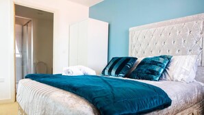 A bedroom with a bed, a wardrobe, and a bathroom door. - Inviting 2-bed Apartment in Wolverhampton (Wolverhampton)
