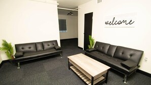 A modern office space with two black leather sofas, a wooden coffee table, and a 'welcome' sign on the wall. - Honeymoon in Hotsprings (Hot Springs)