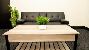 A reception area with a wooden coffee table, a potted plant, a sofa, and a 'welcome' sign on the wall. - Honeymoon in Hotsprings (Hot Springs)