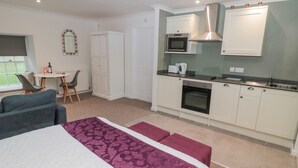 Une chambre d’hôtel de taille réduite comprenant un lit, une petite kitchenette, un coin repas et une salle de bain.
