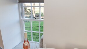 Une table avec une bouteille de vin, deux verres, une boîte de chocolats et une brochure de bienvenue.