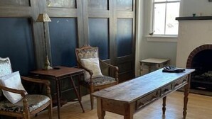 Um quarto com piso de madeira, lareira e uma grande janela.