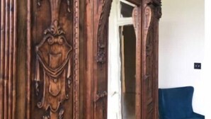 Um armário de madeira com esculturas detalhadas e um vaso.