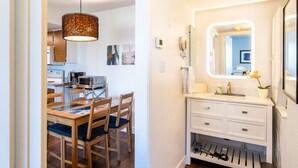 Una cocina moderna con armarios de madera, una mesa de comedor con sillas e iluminación colgante.