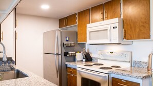 Una cocina moderna con encimeras de granito, electrodomésticos de acero inoxidable, armarios de madera y un microondas integrado.