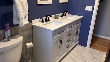 Een bad/douchecombinatie, een haardroger, handdoeken, zeep