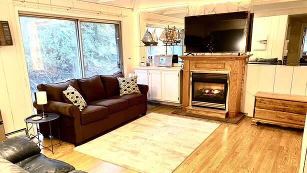 A living room with a brown sofa, a fireplace, and a television. - Spacious House short walk to Bills Stadium (Orchard Park)
