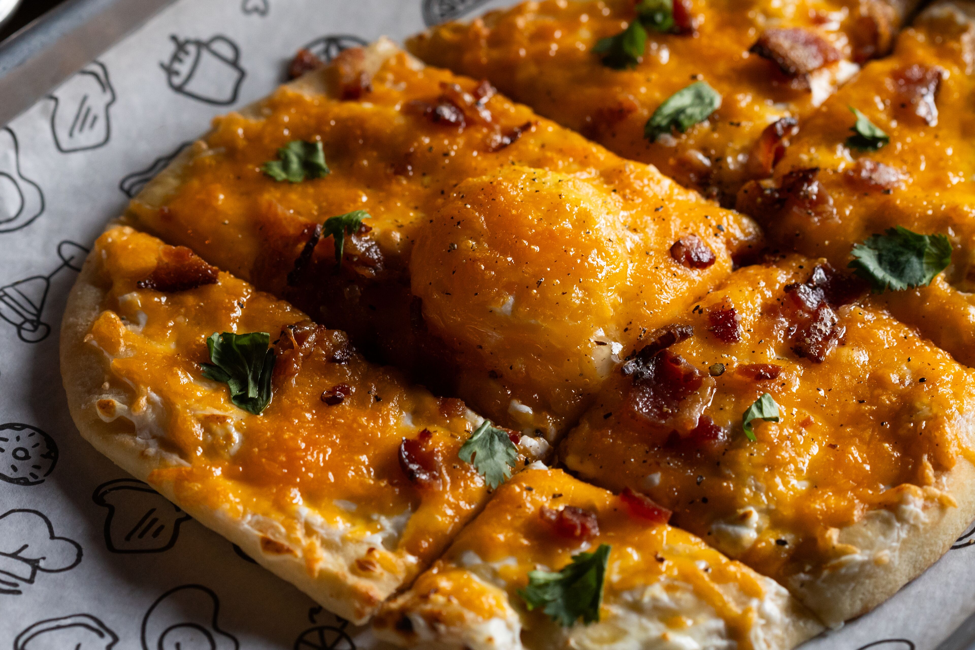 Una pizza con queso, tocino y hierbas.