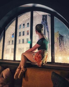 A person sitting by a window with a view of a building. - Moxy Houston Downtown (Houston)