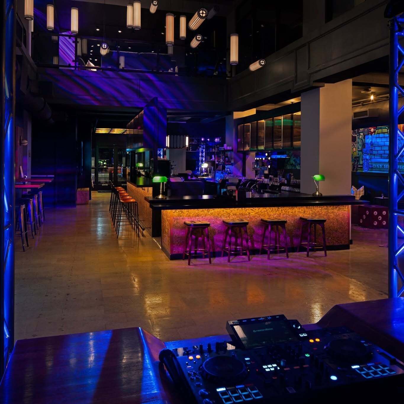 A bar area with stools, a DJ setup, and a bar counter.