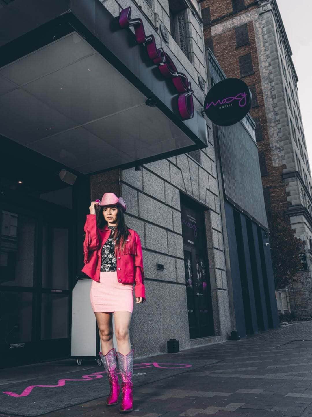 A person standing in front of a building with a sign that reads 'HOTEL.'